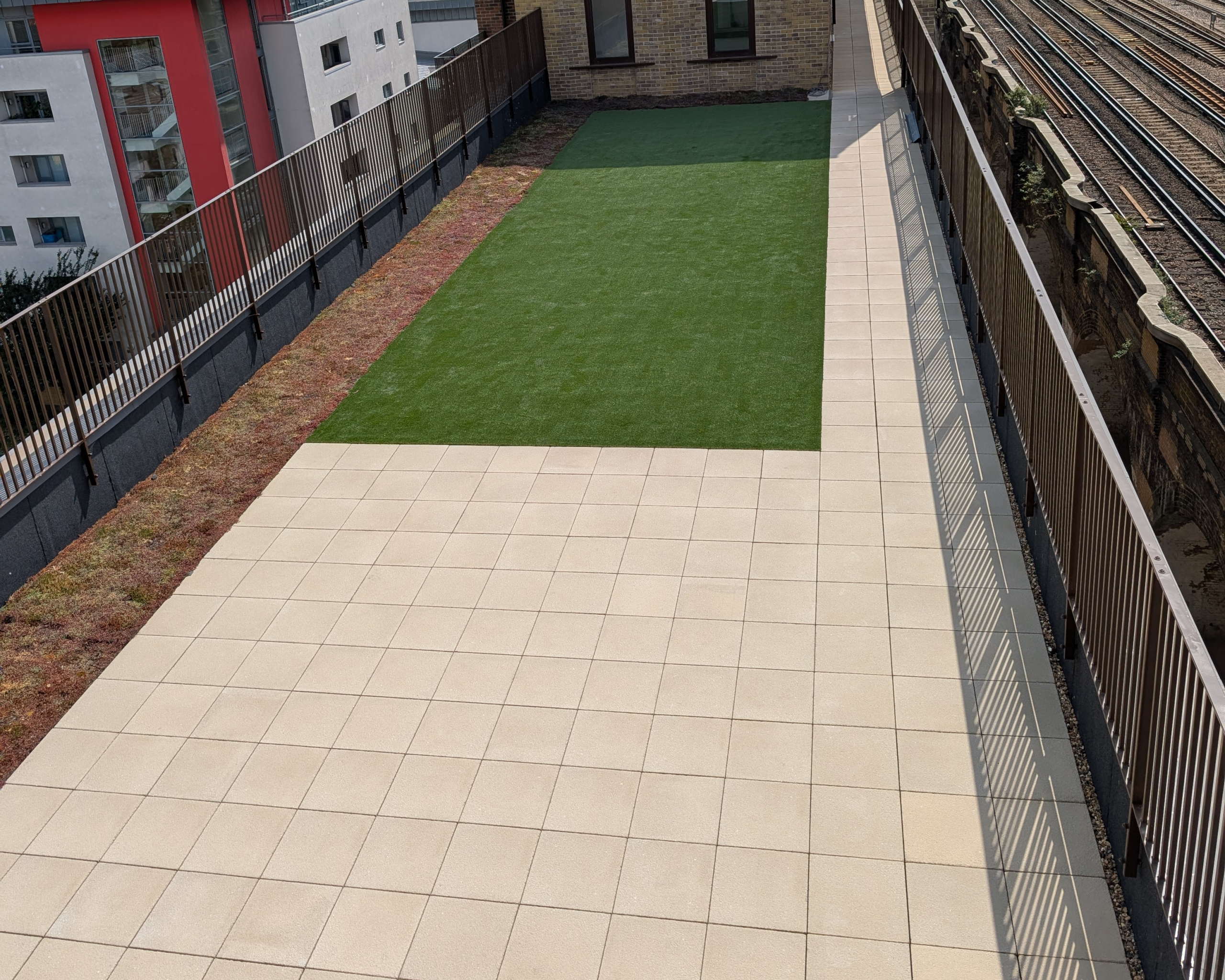 Hot Melt Roofing South East – rooftop deck with central artificial lawn and paved perimeter walkway