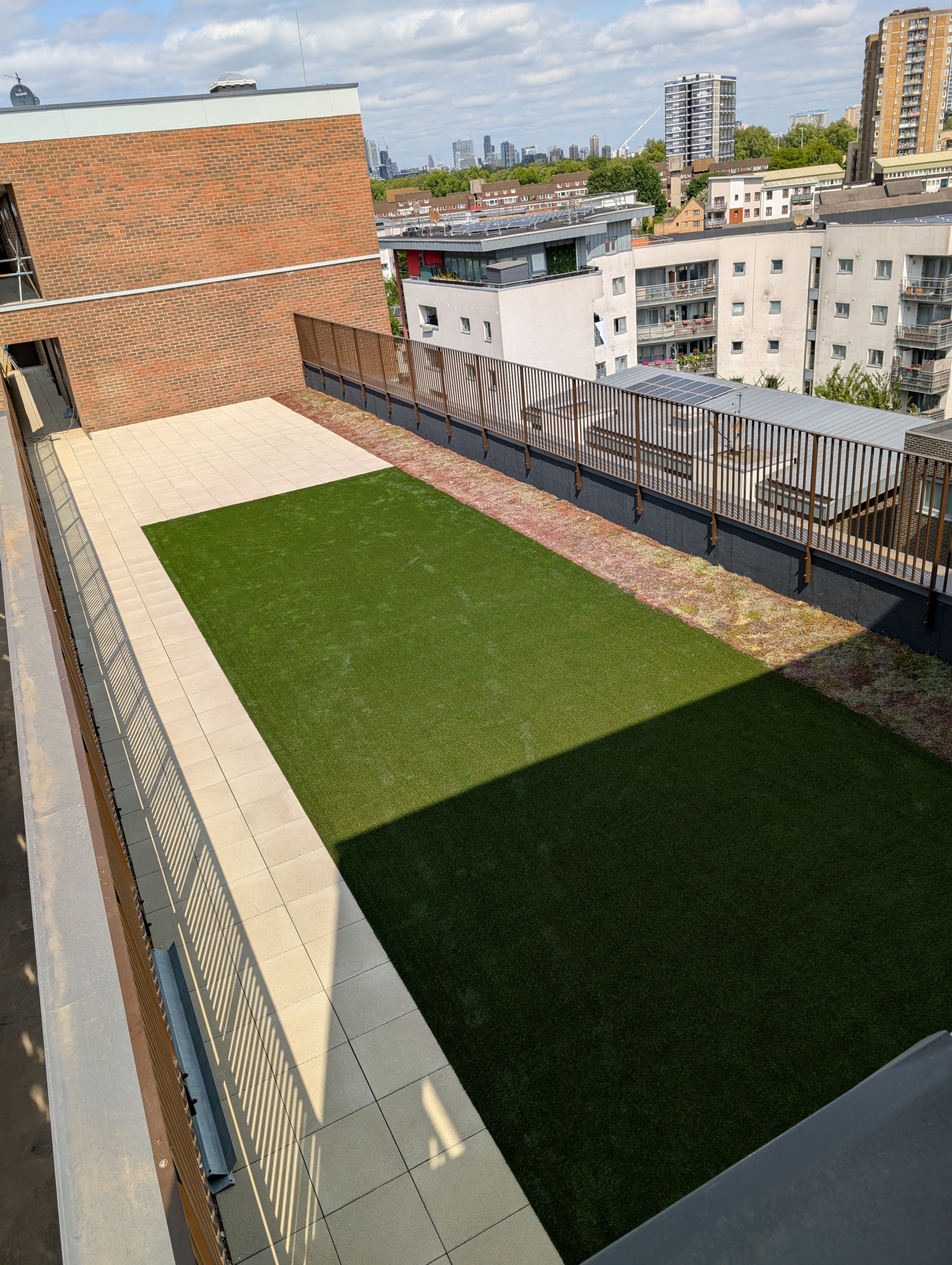 Hot Melt Roofing South East – elevated roof terrace with green landscaping and paving overlooking city buildings
