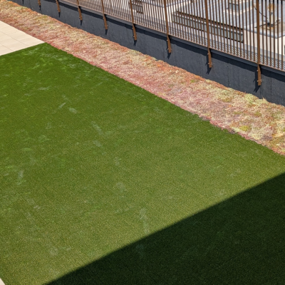 Hot Melt Roofing South East – artificial grass section surrounded by slab paving on rooftop deck