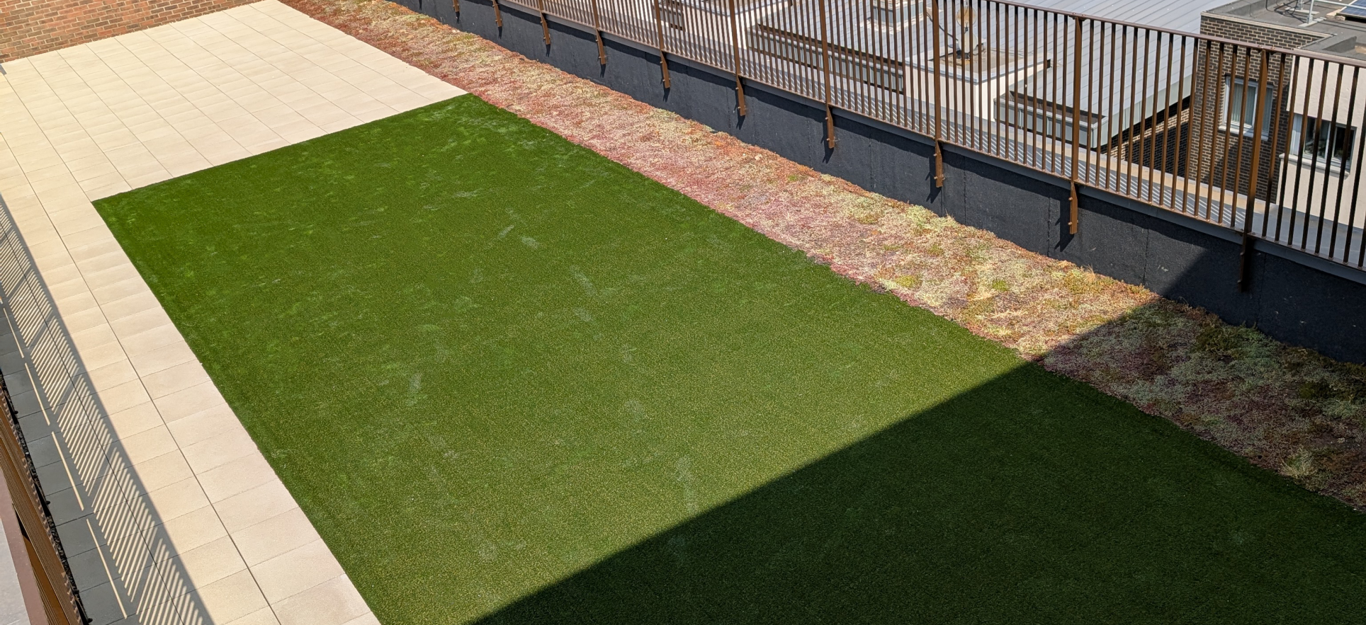 Hot Melt Roofing South East – artificial grass section surrounded by slab paving on rooftop deck