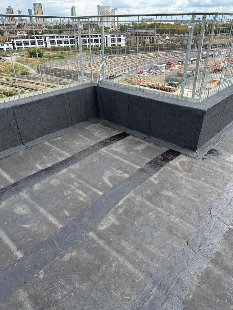 Hot Melt Roofing South East – flat roof installation with parapet detailing overlooking railway tracks