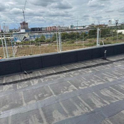 Hot Melt Roofing South East – hot melt flat roof nearing completion on commercial building with city skyline view