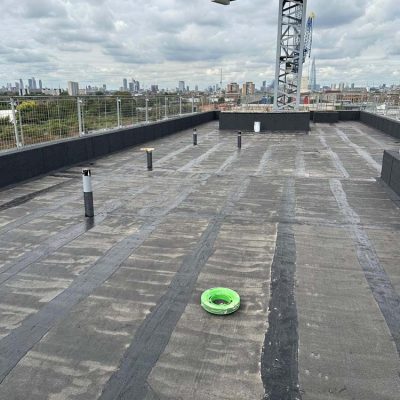 Hot Melt Roofing South East – completed flat roof with hot melt system, vent penetrations, and crane in background
