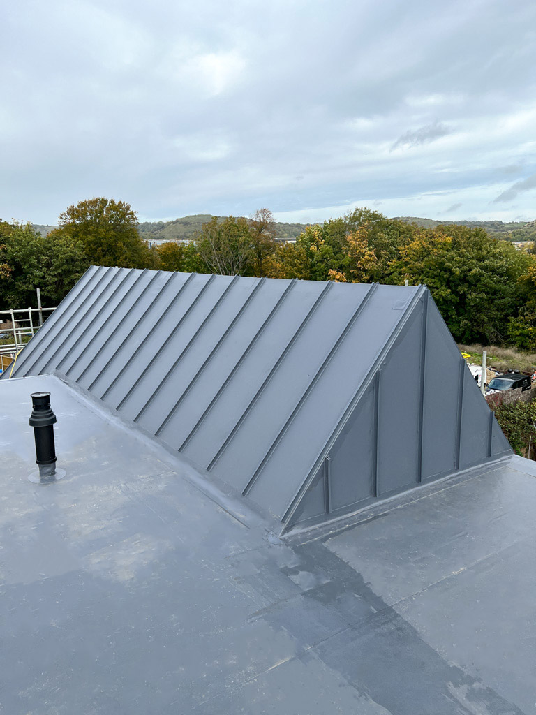 Finished single ply membrane on low-pitched roof with vertical detailing and pipe penetrations