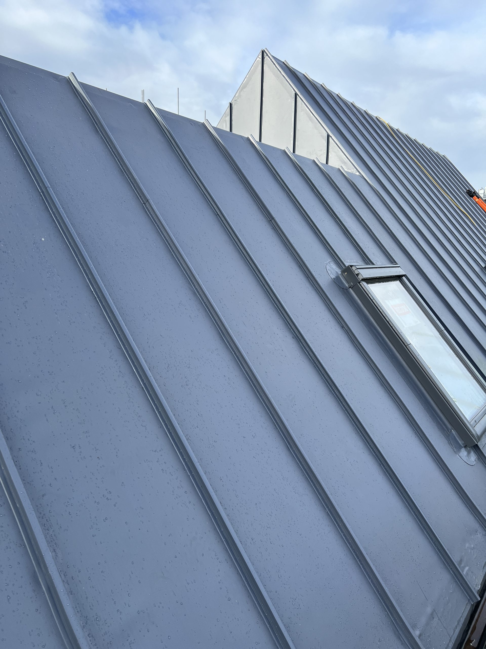 Angled view of single ply roofing membrane on pitched roof with integrated skylight