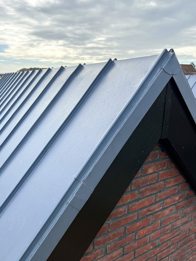 Close-up of vertical single ply roof cladding detail with dark trim on a pitched roof