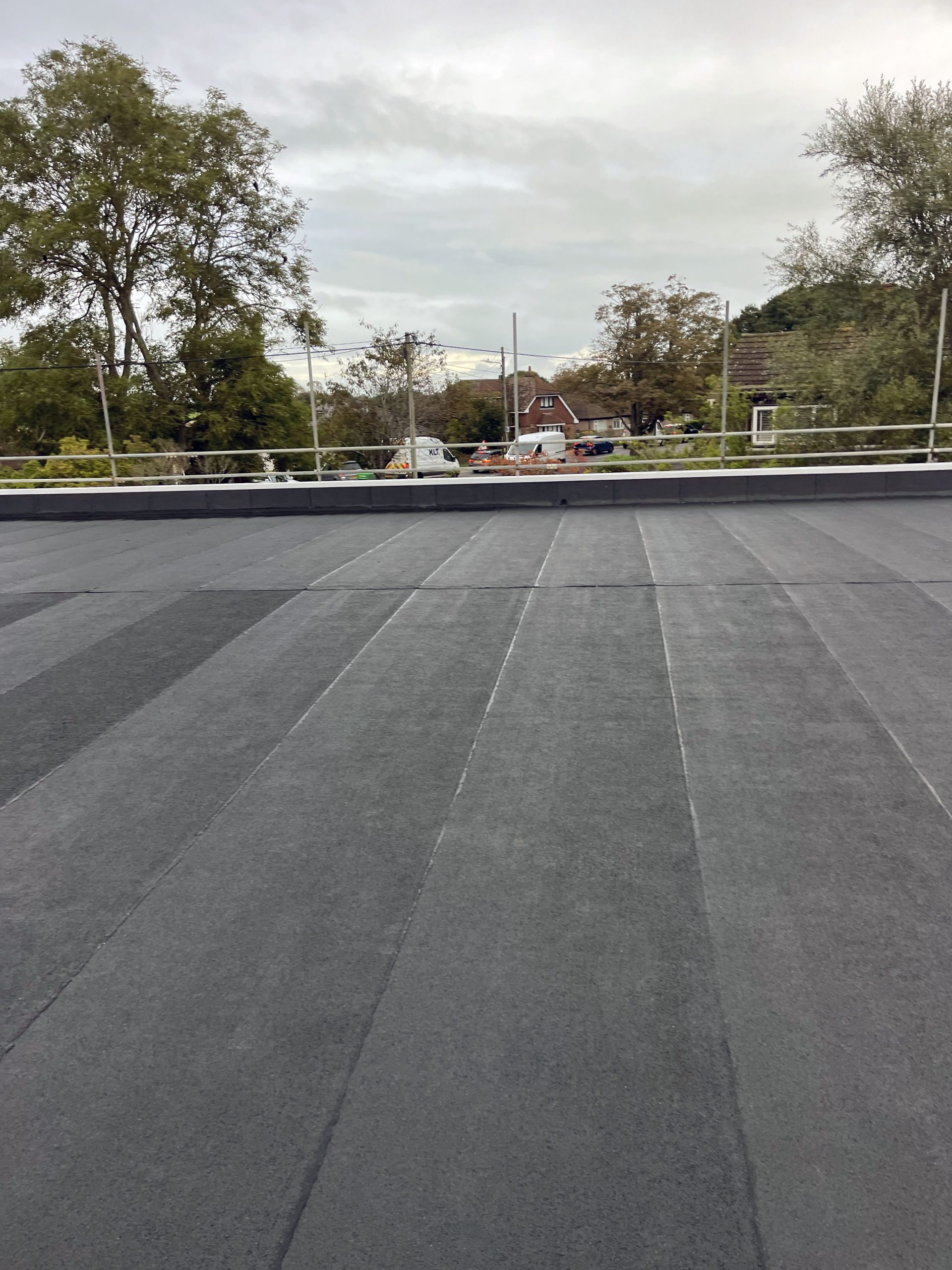 Felt roofing South East – seamless multi-layer felt roof with clean surface finish and trees in background