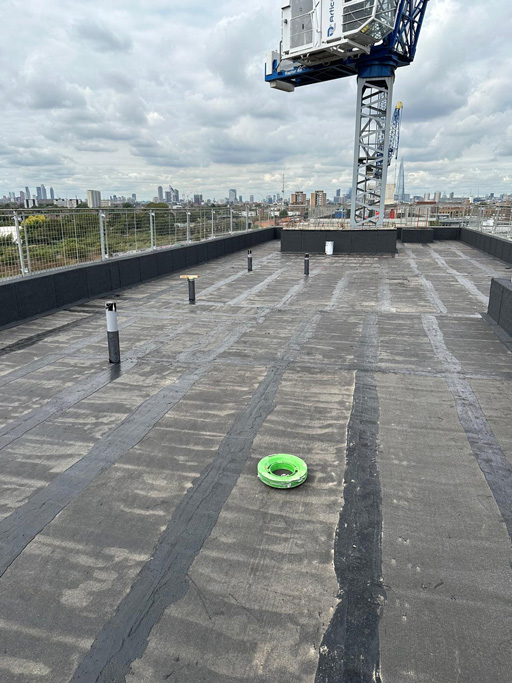 Hot melt roofing South East, installation on a high-rise commercial building with city skyline and crane visible.