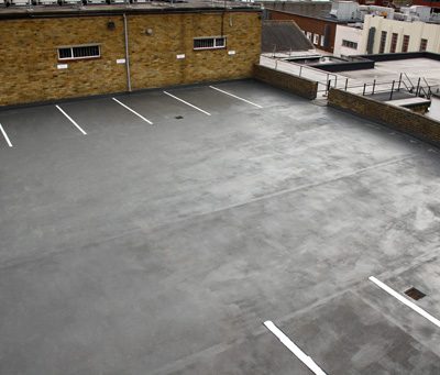 AJ Lucas Roofing services South East UK- Liquid roofing system applied to a flat roof car park with marked parking bays on a commercial building.