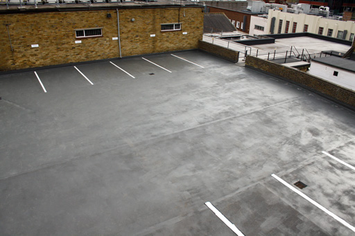 AJ Lucas Roofing services South East UK- Liquid roofing system applied to a flat roof car park with marked parking bays on a commercial building.